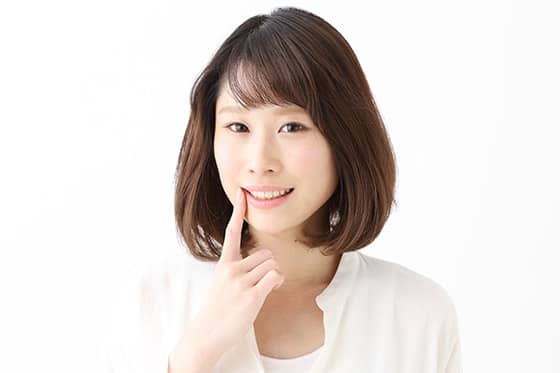 口元を指さす女性