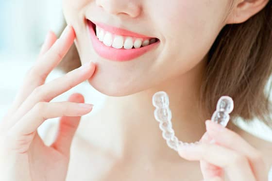 マウスピース型矯正治療を持つ女性